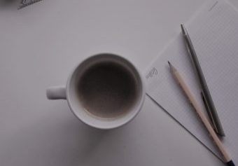 potloden op notitieblok met mok koffie tijdens grip op leren bijles